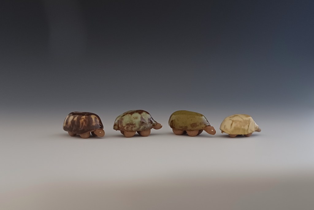 4 small ceramic turtles lined up in a row