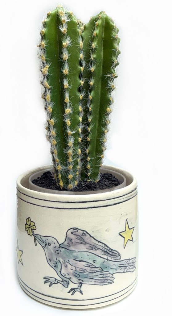 Cactus in ceramic pot decorated with a blue and purple raven