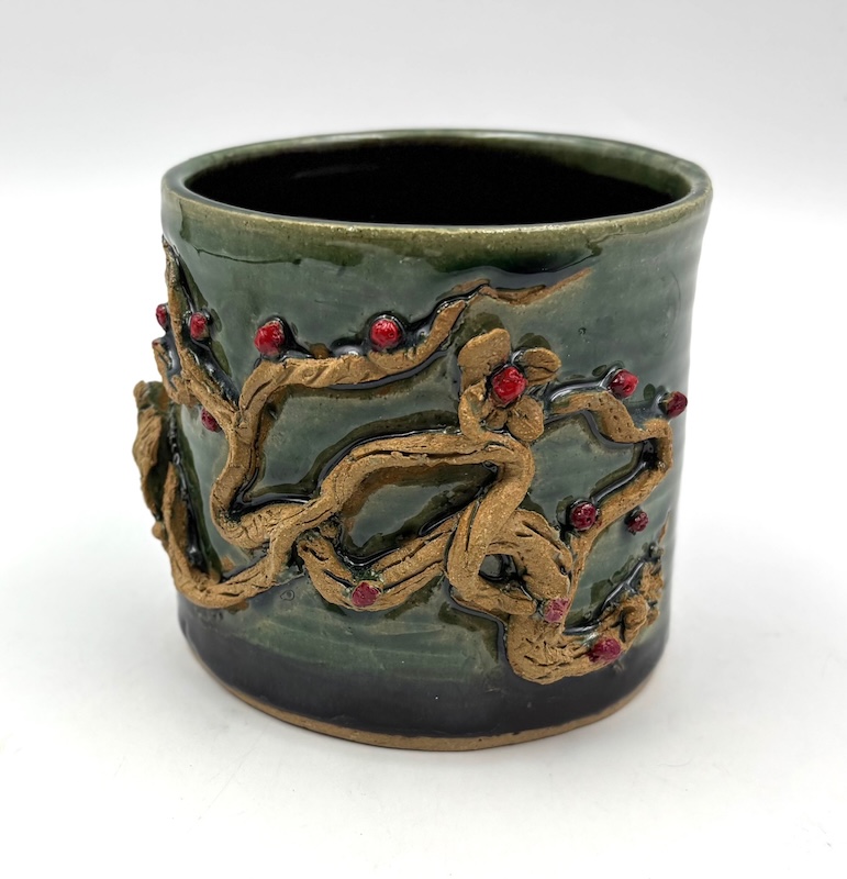 Cylindrical green vessel with vine and red berries decoration
